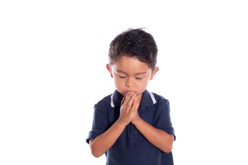 Latin boy praying with closed eyes, isolated on white background. Religious concept. Child praying.