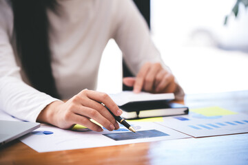 Fototapeta premium businessman or accountant who are using a calculator to calculate business data Accounting documents and laptop computer at the office business idea