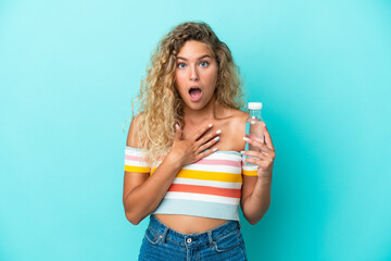 Young blonde woman with a bottle of water isolated on blue background surprised and shocked while looking right