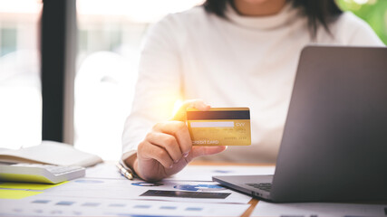 girl holding a credit card and using a laptop Business woman working from home . online shopping, ecommerce, internet banking, spend money, work from home concept.