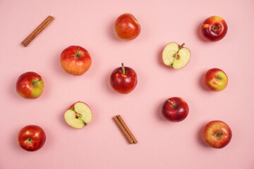 Colorful fruit pattern of fresh red apples with cinnamon on pink background. Flat lay, top view, copy space for your text. Healthy concept