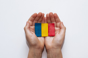 flag of Romania made of plasticine in the hands of a child on a white background
