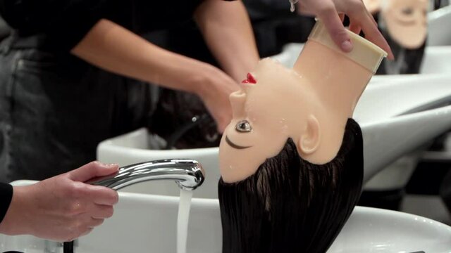 students wash the hair of mannequins at a hairdressing course