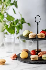 Fototapete Rund Two tier cake  stone stand with tasty french  mixed macarons and strawberry berries on marble table. © BarTa