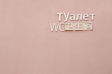 pink wall with toilet inscription in Russian, Chinese and English