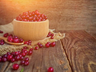 Ripe fresh cranberries in a wooden bowl on a rustic table top.