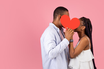 Young Romantic Black Couple Kissing Hiding Behind Red Paper Heart