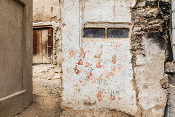 Red hand prints on a traditional stucco building.