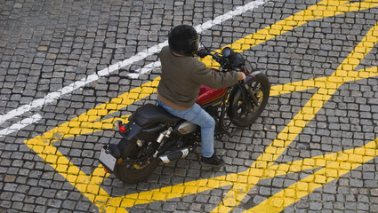Motociclista montado na mota parado dentro do losango do rectângulo de proibição de paragem - contraste de cores e cruzamento de linhas