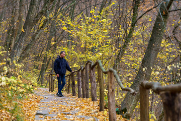 young man enjoys a beautiful view and unity with nature in the autumn forest. Background with copy...