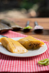 Tamale cut in half on a white plate. Copy space. Corn-based food.