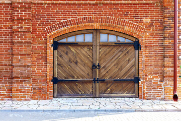 red brick wall with arch and wooden gate