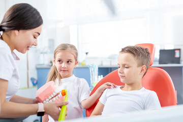pediatric dentist shows young children how to brush their teeth properly. Children - a boy and a girl in doctor's office. concept is health of children's teeth.