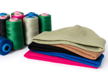 Stylish handmade hats made of eco material in actual colors with spools of thread on a white background