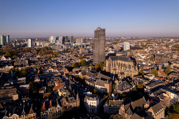 Aerial view of De Dom medieval cathedral in scaffolding in Dutch city centre of Utrecht with cathedral towering over the city against a blue sky with clouds