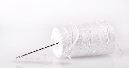 spool with white thread and a needle.