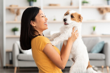Portrait of cheerful chinese woman carrying her sweet dog