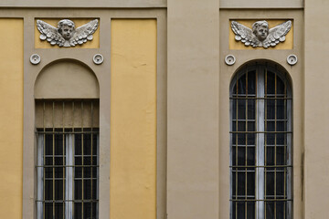 Detail of the exterior of a church with high arched windows and bas-reliefs representing putti, Parma, Emilia-Romagna, Italy