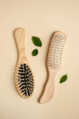 two wooden combs on a beige background with green leaves in a vertical format