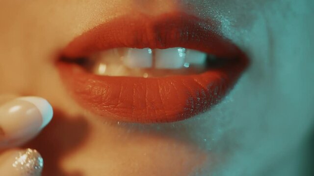 A disappointed woman is smearing red lipstick on face with hand. Female protest. Rubbed and bad makeup. Conceptual art. Close up of female lips.