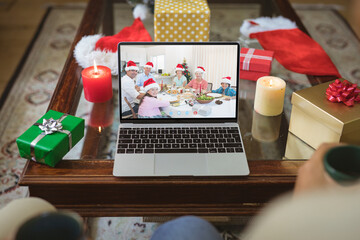Smiling multi generation caucasian family in santa hats on laptop christmas video call screen