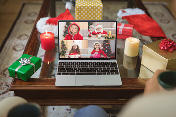 Four smiling caucasian children in santa hats on laptop christmas group video call screen