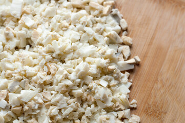 Finely diced boiled chicken eggs on a wooden cutting board with blurred edges