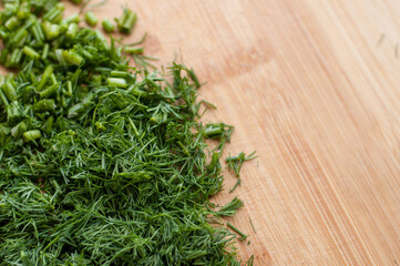 Finely chopped fresh dill on a wooden cutting board with blurred edges