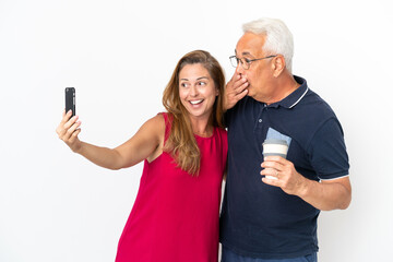 Middle age couple isolated on white background making a selfie with the mobile