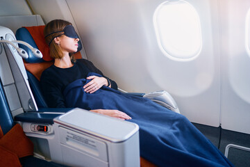 Traveling at first class. Flight with comfort. Pretty young  woman sleeping in airplane.