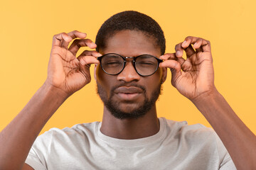 African american man with poor eyesight wearing eyeglasses and squinting eyes while looking at...