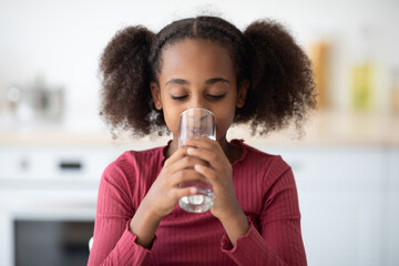 Pretty black girl drinking water, kitchen interior