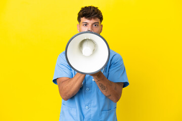 Young surgeon doctor man isolated on yellow background shouting through a megaphone