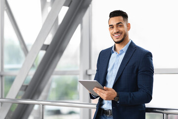 Fototapeta premium Modern Entrepreneurship. Handsome Arab Businessman With Digital Tablet Posing At Airport Terminal