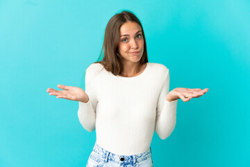 Young woman over isolated blue background having doubts while raising hands