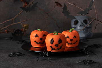 Dessert for Halloween - sweet pumpkin-shaped mousse cakes on a dark background with a decor of...