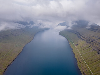 Beautiful view of the Faroe Islands roads - highways across the huge mountains and the ocean canals and small villages 