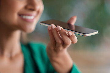 Unrecognizable smiling woman recording voice message on cellphone
