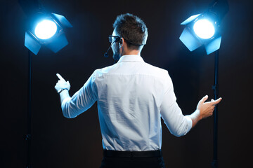 Motivational speaker with headset performing on stage, back view