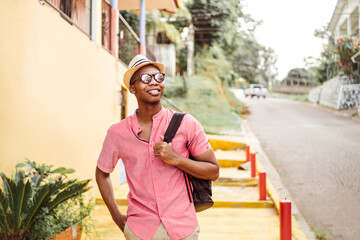 black young adult tourist go with eyeglasses holding a backpack walking on latin american...