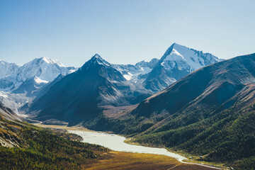 Wonderful alpine landscape with mountain lake and mountain river in valley with forest in autumn...