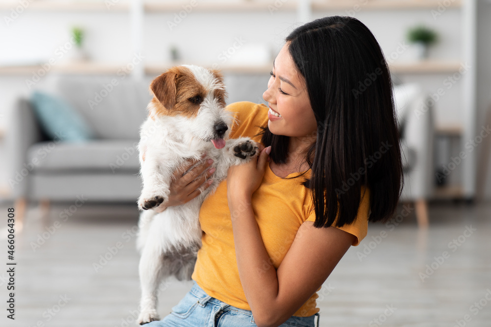 Wall mural Closeup of attractive asian woman cuddling with her doggy