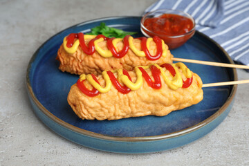 Delicious corn dogs with mustard and ketchup served on light table, closeup