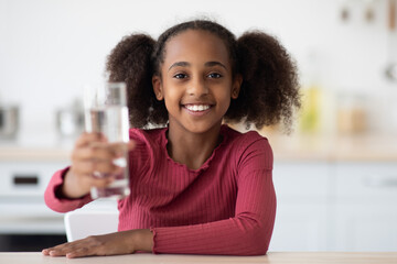 Cheerful african american girl teenager holding glass of fresh water