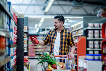 Young handsome man in a supermarket grocery shopping
