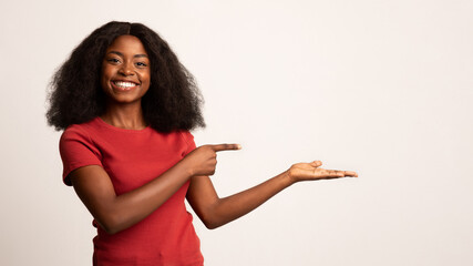 Check This. Cheerful Young Black Lady Pointing At Her Open Empty Palm