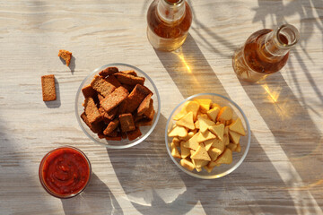 Different crispy rusks, beer and dip sauce on wooden table, flat lay