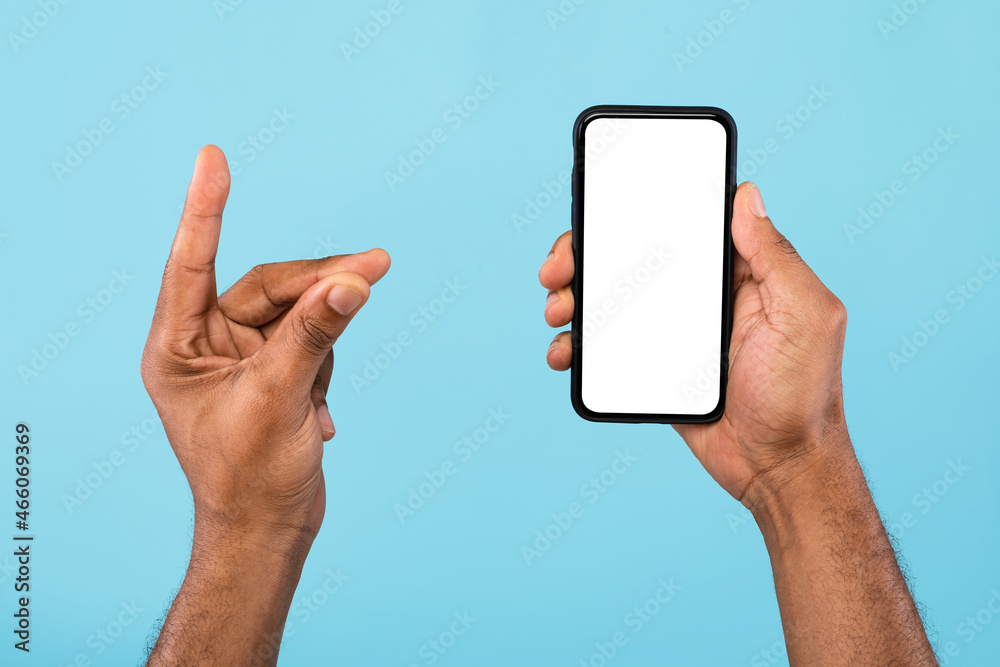 Poster cropped view of young black guy showing smartphone with empty white screen and holding something, mo