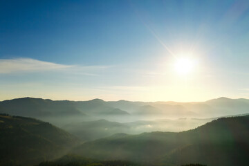 Sun shining over forest in misty mountains. Drone photography