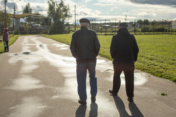 Pensioners walk in the autumn in the park. People are outside in early autumn.